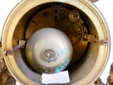 a gold clock with a white ball inside of it