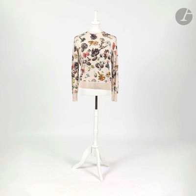 un mannequin blanc portant un pull à motifs floraux, posé sur un socle blanc