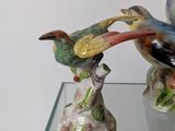 two figurines of birds on a glass shelf