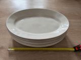 plusieurs assiettes blanches empilées les unes sur les autres sur une table en bois