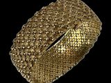 a close up of a gold bracelet on a black background