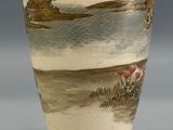a vase with a painting on it sitting on a table