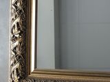 a gold framed mirror on the wall above a sink