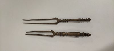une paire de couteaux anciens à manche en laiton posés sur une surface blanche
