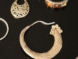 many different types of silver jewelry on a black table