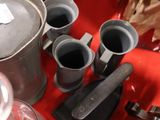 a red table cloth with a bunch of cups and a kettle on it