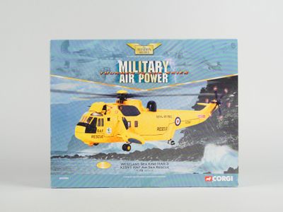 hélicoptère militaire miniature dans sa boîte, posé sur une surface blanche