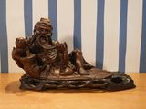 une statue représentant un homme assis dans un bateau avec un chien