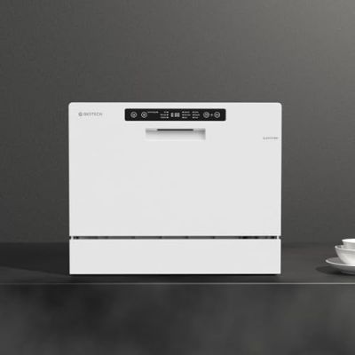a white dishwasher sitting on top of a counter next to a cup of coffee