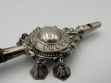 a silver object with bells on it on a white surface