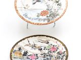 two plates with birds and flowers painted on them on a white surface