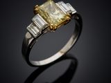 a yellow diamond and diamond ring with baguets on a black background