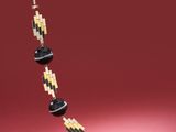 un collier de perles noires et jaunes sur un fond rouge