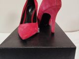 des chaussures à talons hauts roses posées sur une boîte noire, elle-même posée sur une surface blanche