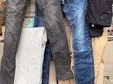 Plusieurs paires de jeans sont empilées sur une palette devant un bâtiment