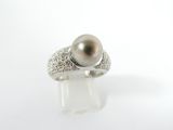 gros plan d'une bague en perles et diamants sur une surface blanche
