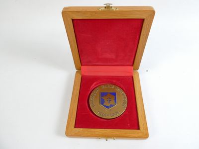 une image représentant une médaille d'or dans un coffret en bois posé sur une surface blanche