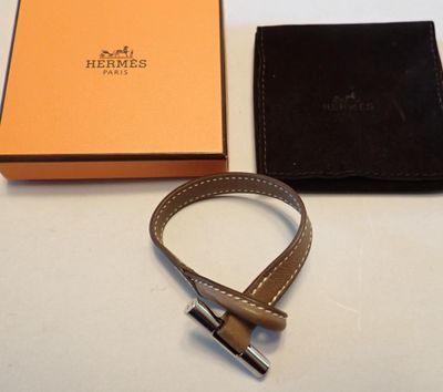 La ceinture en cuir marron se trouve à côté d'une boîte orange et d'un portefeuille noir