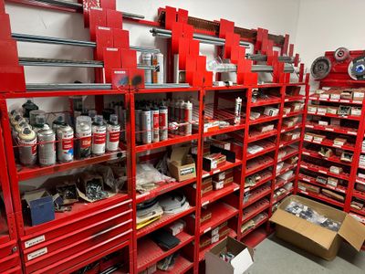 many red shelvings in a room with many cans of paint
