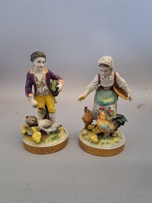 paire de figurines représentant un garçon et une fille accompagnés de poulets