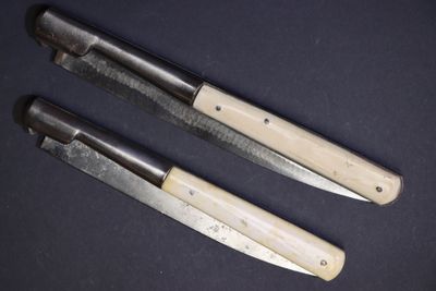 trois couteaux sont posés sur une table sur fond noir