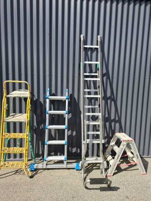several ladders are lined up in front of a metal building