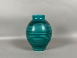 un vase vert posé sur une surface blanche