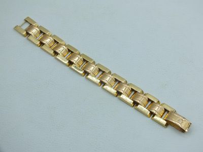 a close up of a gold bracelet on a white surface