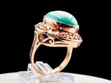 an image of a gold ring with a green stone in it
