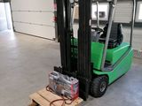 un chariot élévateur vert garé à l'intérieur d'un bâtiment