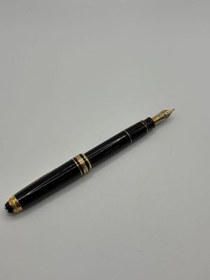 un stylo-plume noir et doré posé sur une table blanche