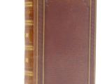 an old book with a brown cover sitting on top of a white surface