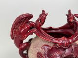 a red vase with a dragon on it on a table