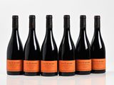 six bottles of wine are lined up in a row on a white surface