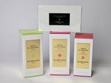 trois boîtes de parfum posées les unes à côté des autres sur une surface blanche