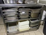 several pans and pans are stacked on a metal shelf in a kitchen