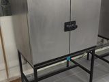 two stainless steel ovens sitting on a stand in a kitchen