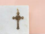 une croix en or posée sur un bloc de marbre, sur fond rose