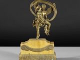 une figurine antique en bronze représentant un Cupidon tenant un oiseau