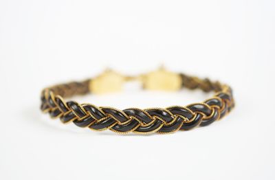 un bracelet tressé noir et doré sur fond blanc