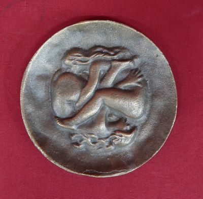 a silver coin with a dragon on it on a red surface
