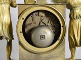 a gold clock that has two statues on top of it
