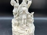 une statue blanche représentant une femme et deux enfants posée sur un gâteau