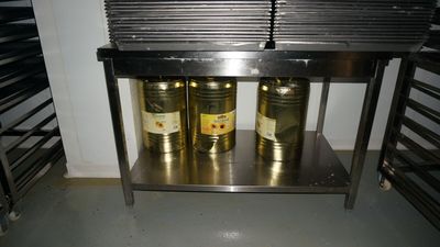 two bottles of olive oil sitting on a metal shelf