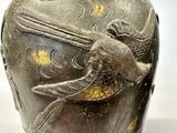 a vase with a bird on it sitting on a table