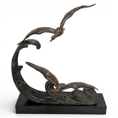bronze sculpture of two seagulls flying over a wave on a black base