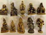 Des figurines de Bouddha en laiton sont exposées sur une surface blanche