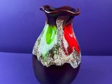 a colorful vase sitting on a purple surface