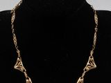a gold necklace on a mannequin neck with a black background