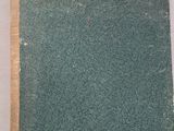 un livre à la couverture verte posé sur une surface blanche